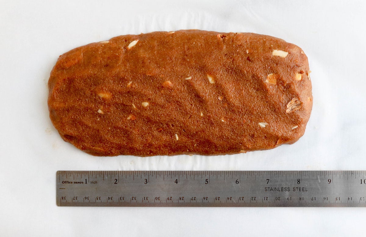 biscotti loaf next to a metal ruler on a pan.