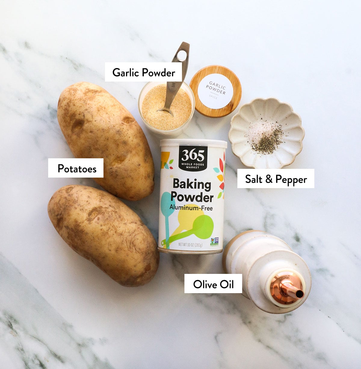 potatoes, baking powder, olive oil, and spices labeled on a white surface.