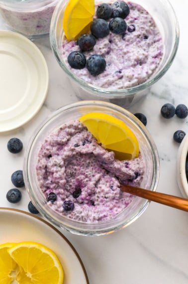 blueberry chia pudding in two jars topped with lemon slices.