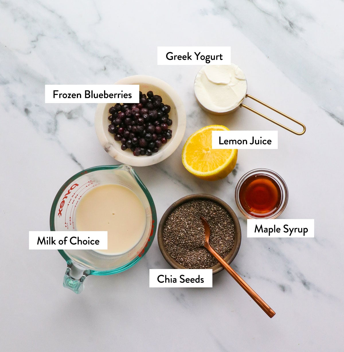 chia seeds, milk, frozen blueberries, yogurt, and maple syrup labeled in bowls. 