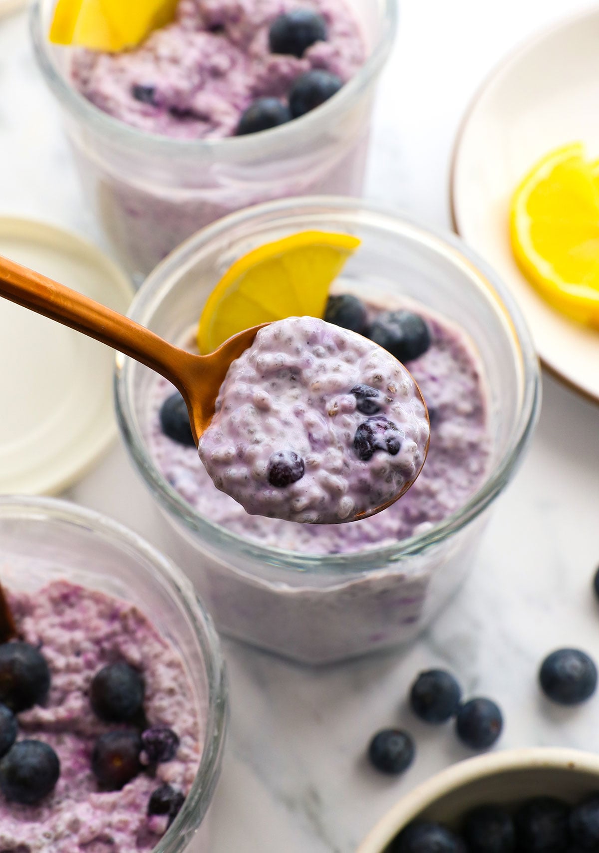 blueberry chia pudding lifted on a spoon over the jar.