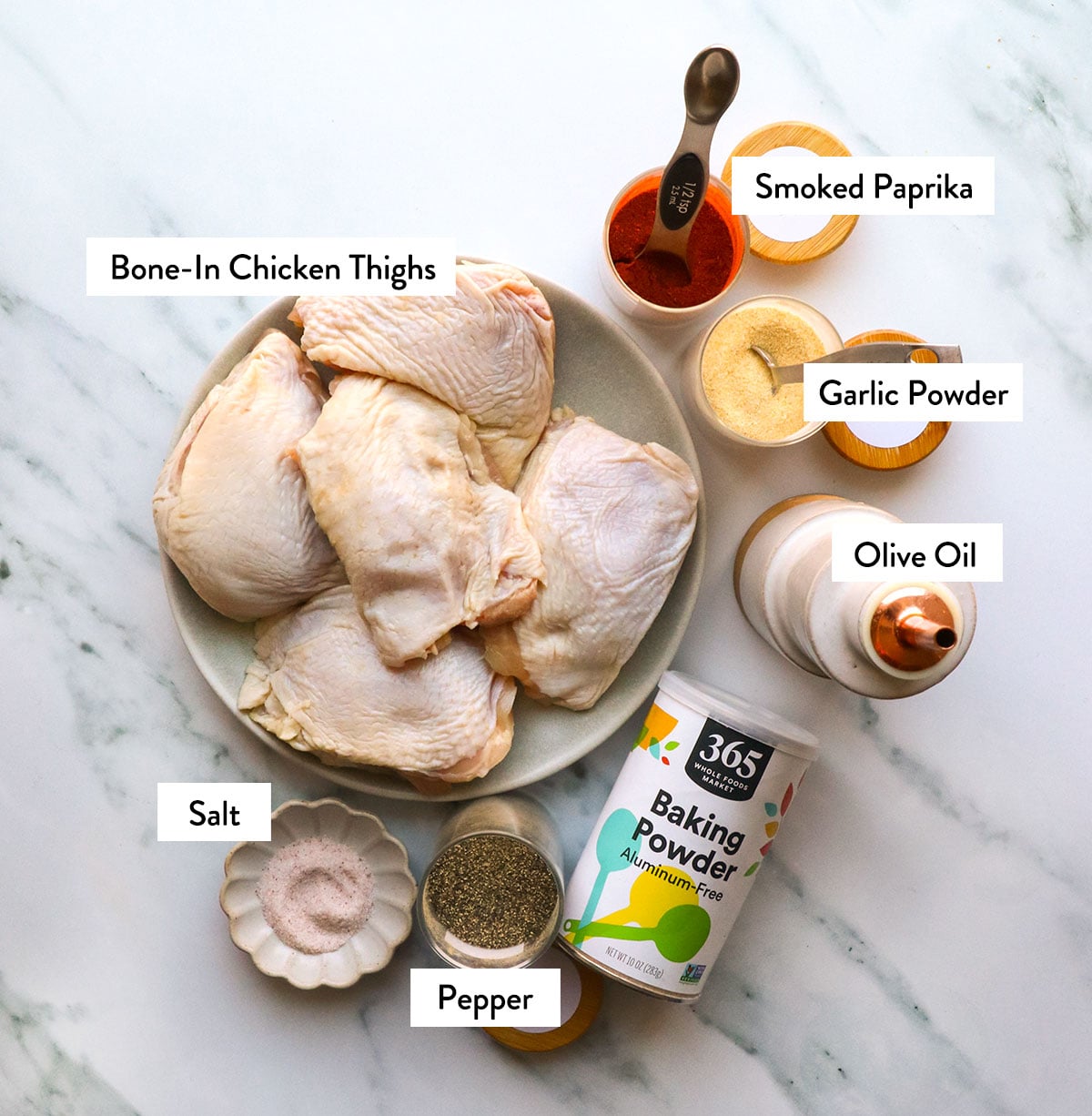 bone in chicken thighs on a plate with spices and olive oil nearby.