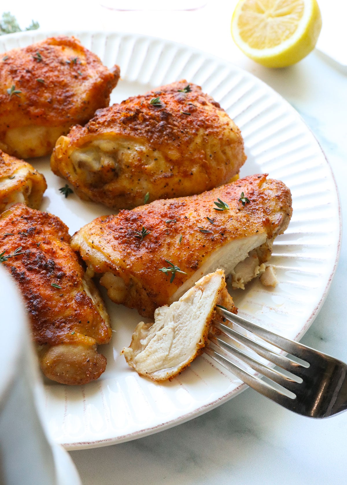 crispy bone in chicken thighs cut on a plate with a fork.