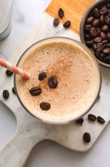 coffee smoothie topped with cacao powder and coffee beans.