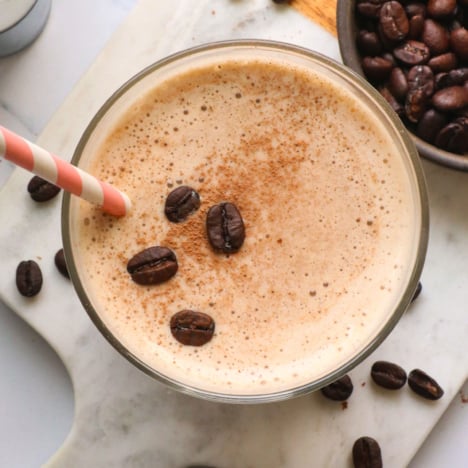 coffee smoothie topped with cacao powder and coffee beans.