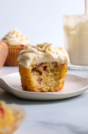 cream cheese frosting on a cranberry muffin with a bite removed.