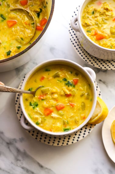 chicken curry soup served in two bowls with a silver spoon.