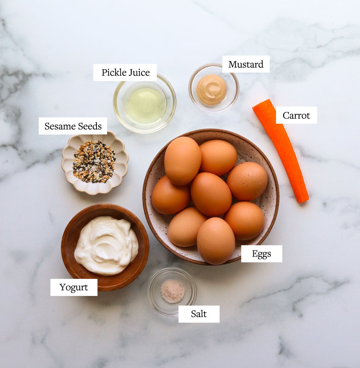 Easter deviled egg ingredients labeled on a marble surface.