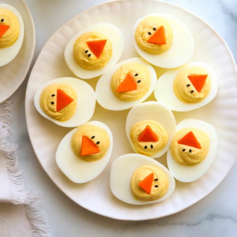 Easter deviled eggs served on a white plate overhead.