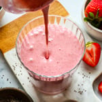 chia seed smoothie poured into a glass with strawberries nearby.