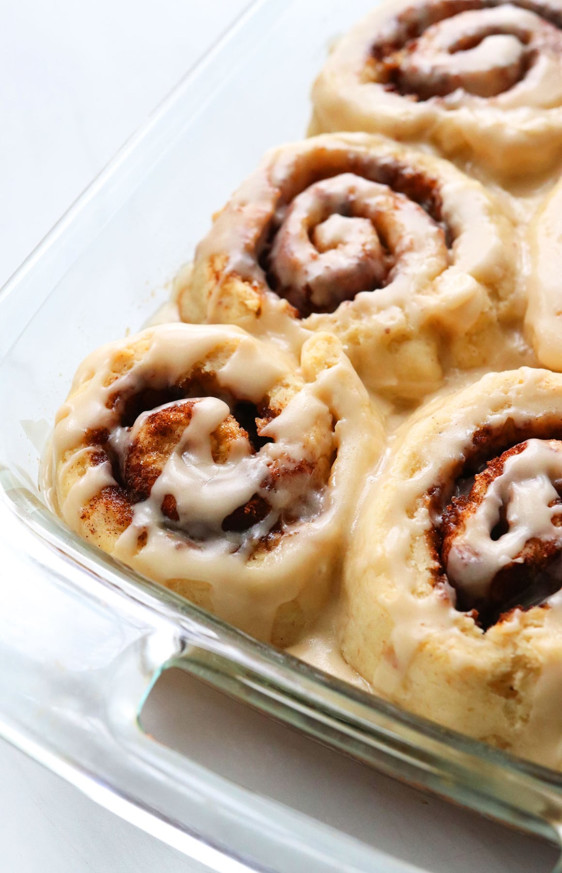 the best gluten-free cinnamon rolls in a glass pan topped with frosting.