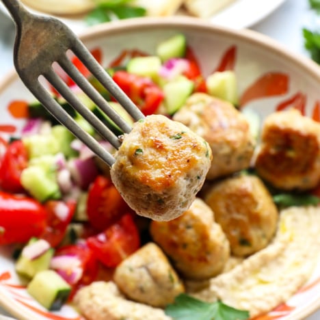 Greek chicken meatball lifted on a fork.