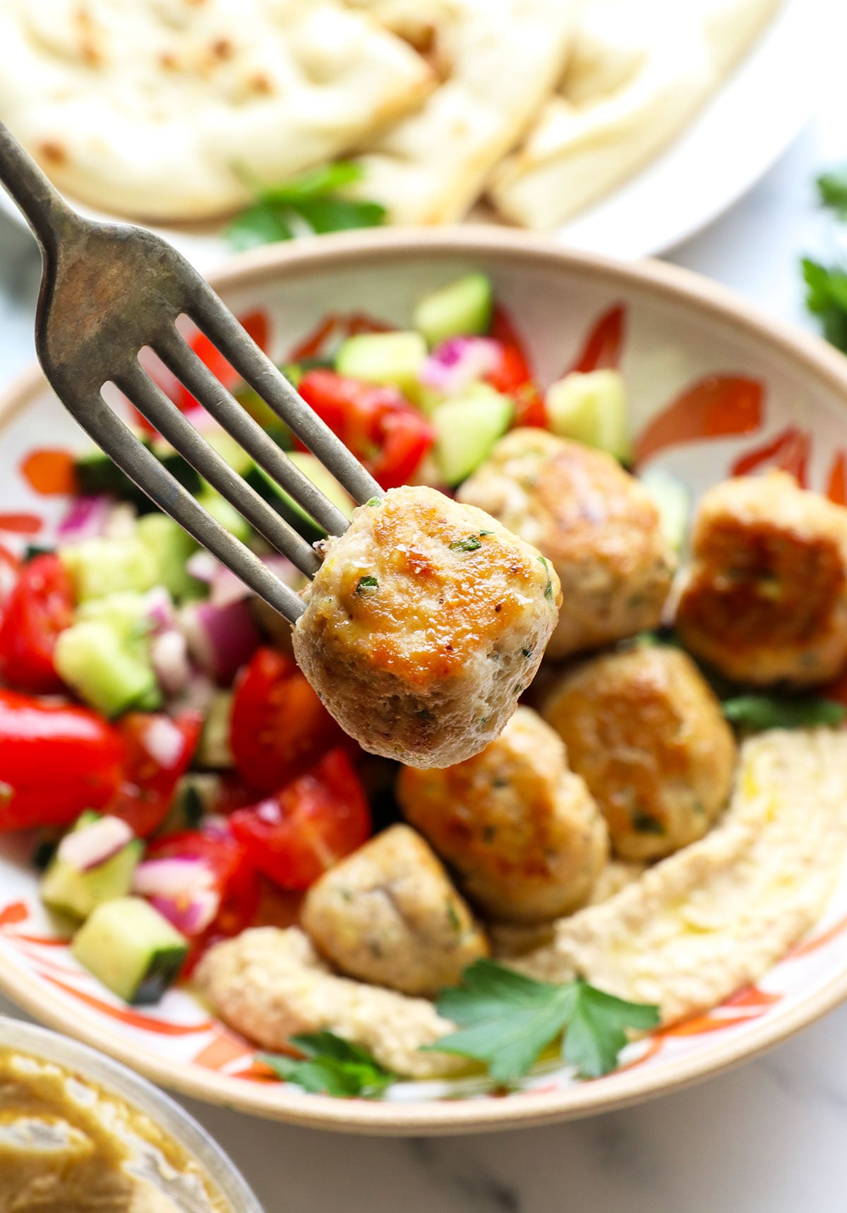 Greek chicken meatball lifted on a fork. 
