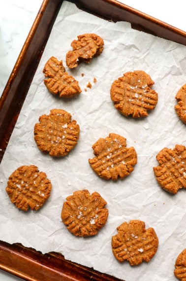 healthy peanut butter cookies on a baking sheet with salt.
