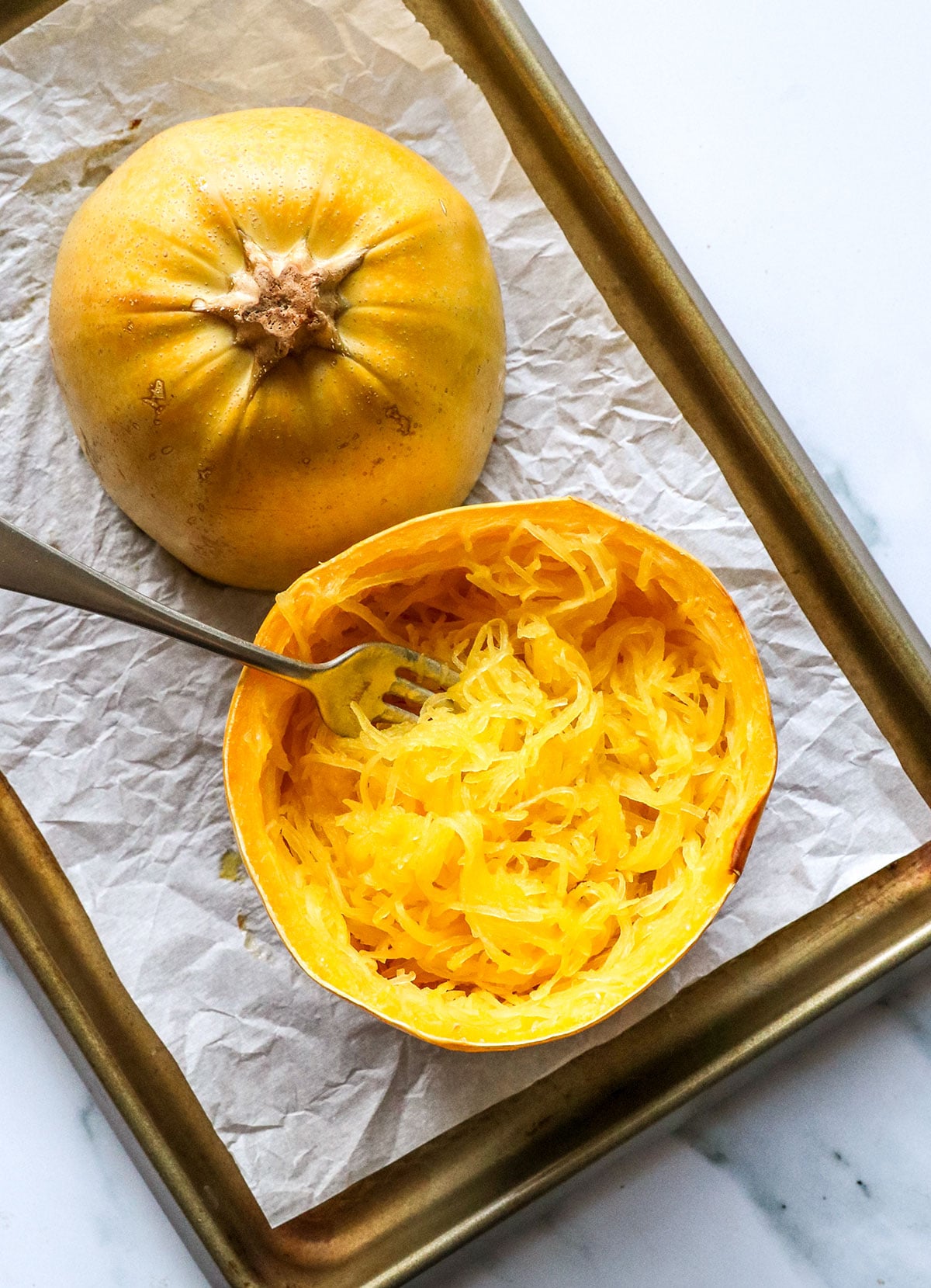spaghetti squash prepared on a baking sheet and fluffed with a fork.