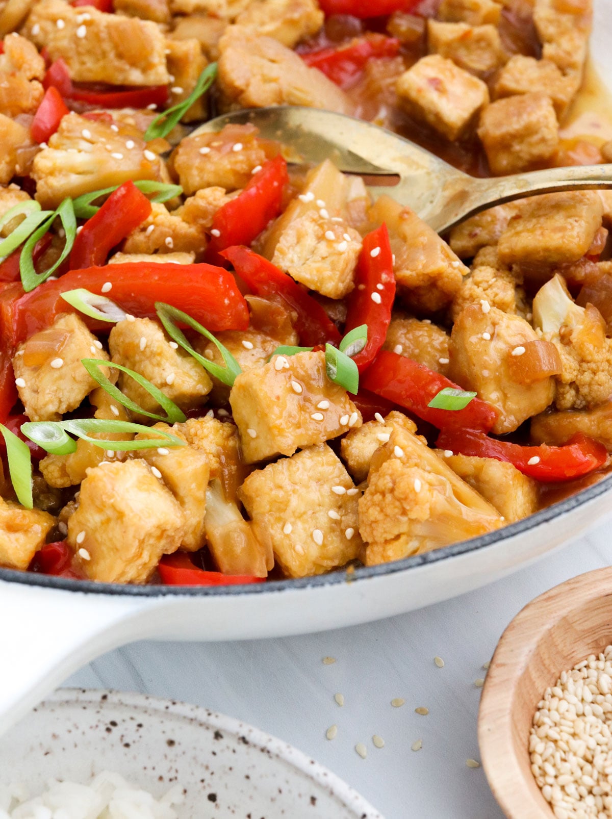 vegan orange chicken in a skillet with spoon.