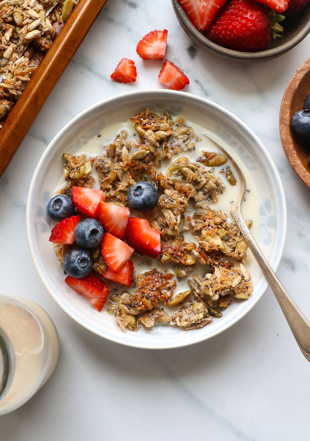 paleo granola served with almond milk and berries in a bowl.