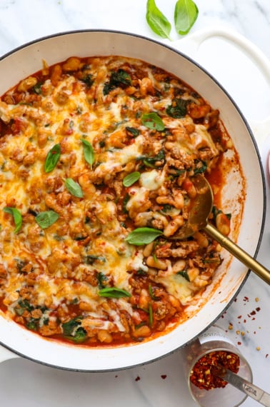 pizza beans with ground turkey served in a skillet with fresh basil.