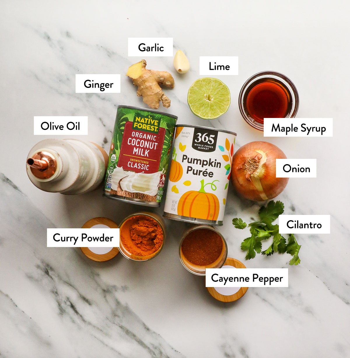 pumpkin, coconut milk, curry powder, lime, garlic, and ginger labeled on a white surface.