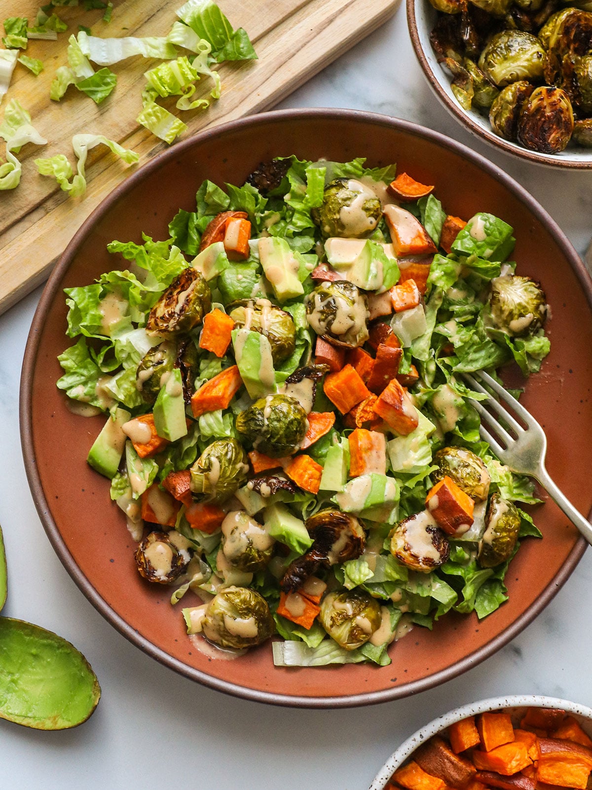 roasted vegetable salad topped with sweet potato, avocado, brussels sprouts and dressing.