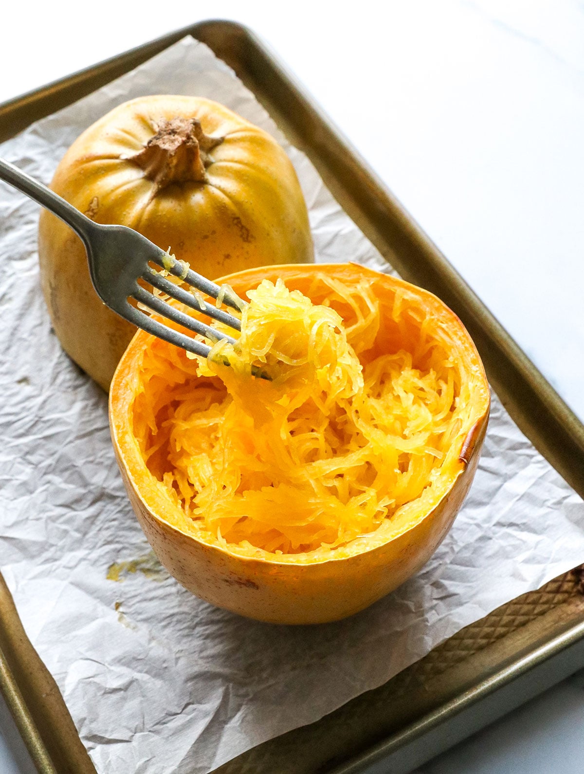 spaghetti squash noodles lifted on a fork after scraping the squash.