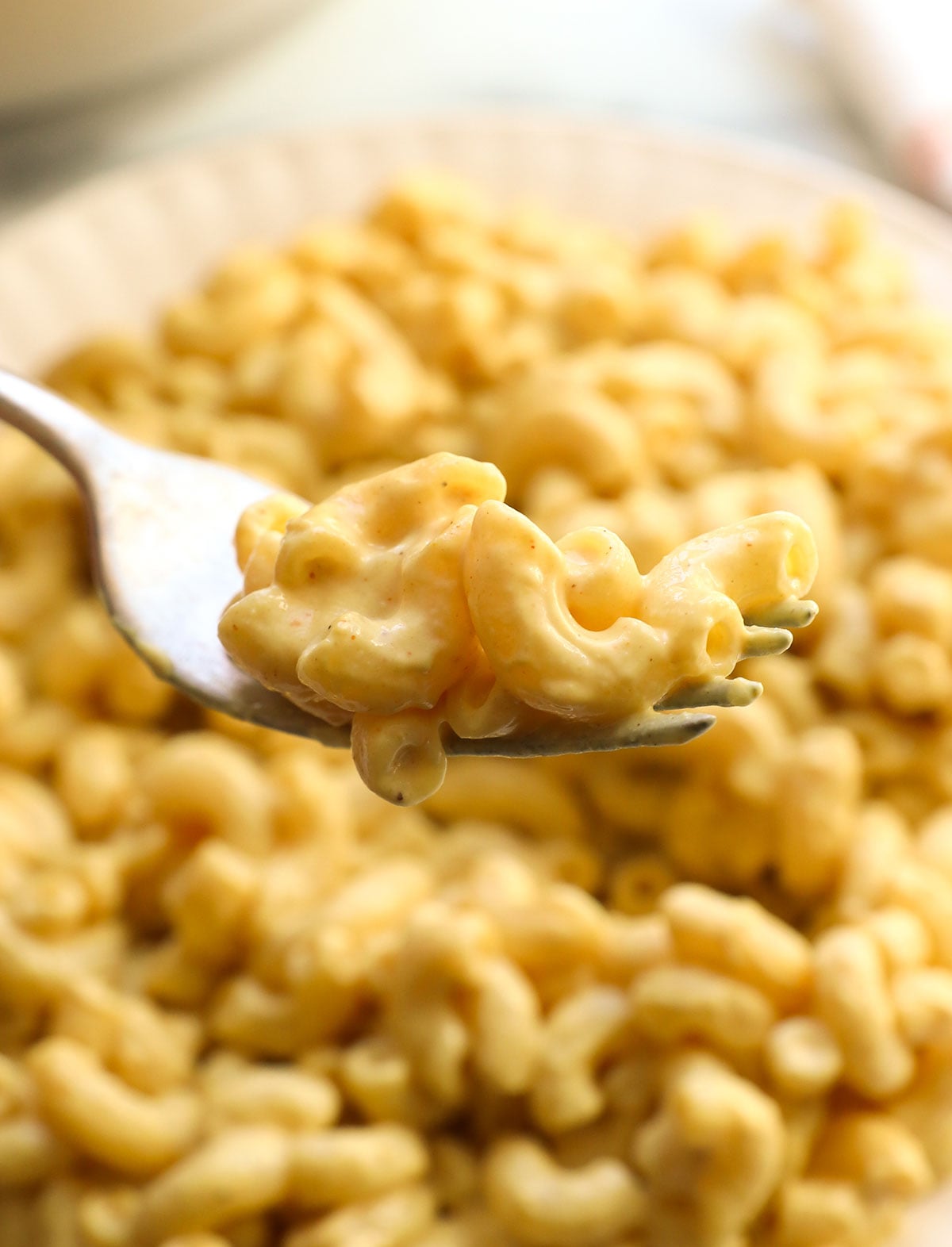 vegan mac and cheese lifted close up on a fork.
