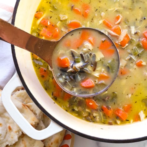 chicken wild rice soup on a ladle over a pot of soup.