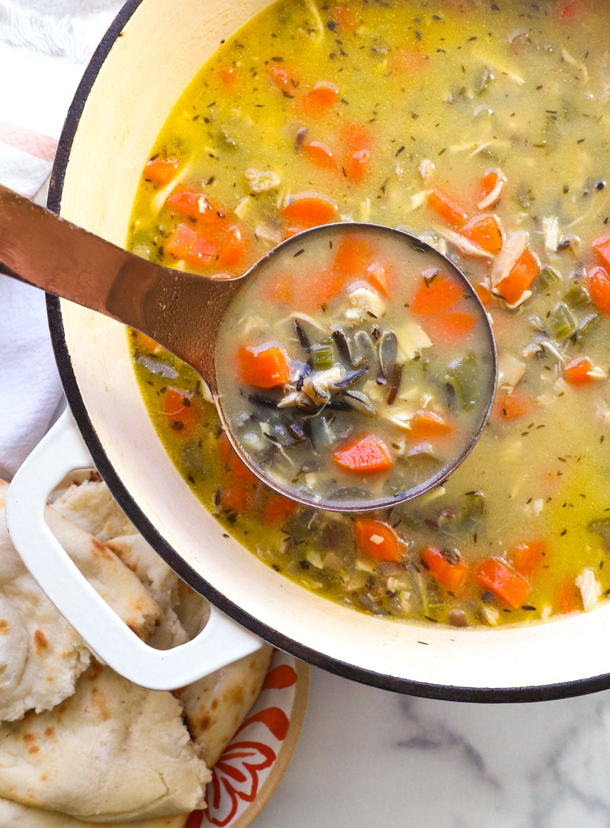 chicken wild rice soup on a ladle over a pot of soup.
